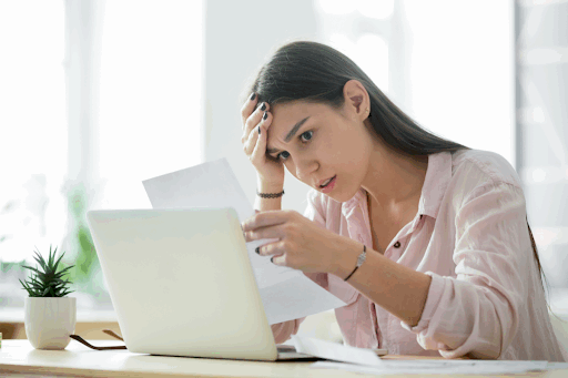 Stressed-out woman looking at a letter and rubbing her forehead.